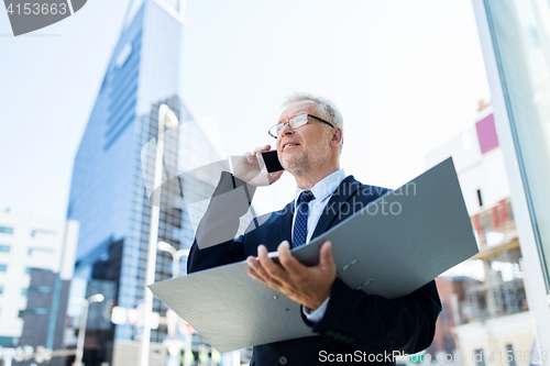 Image of senior businessman calling on smartphone in city