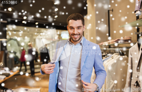 Image of happy young man trying jacket on in clothing store