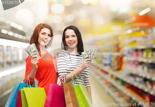 Image of smiling teenage girls with shopping bags and money