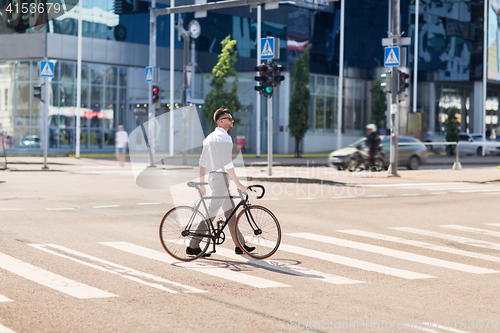 Image of young man with bicycle on crosswalk in city