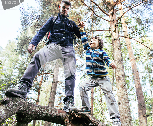 Image of little son with father climbing on tree together in forest, lifestyle people concept, happy smiling family on summer vacations