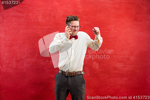 Image of Portrait of puzzled man talking by phone a red background