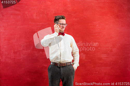 Image of Portrait of puzzled man talking by phone a red background