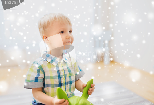 Image of happy baby boy playing with ride-on toy at home