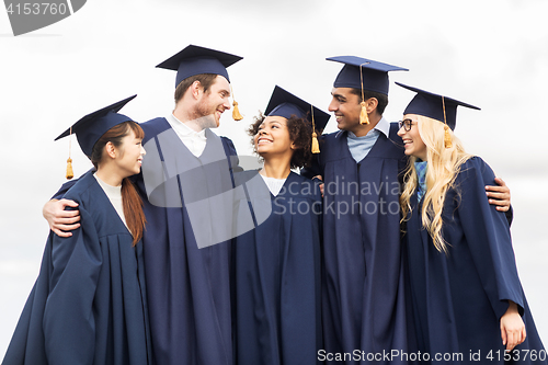 Image of happy students or bachelors in mortar boards