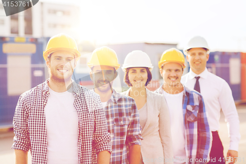 Image of group of smiling builders in hardhats outdoors