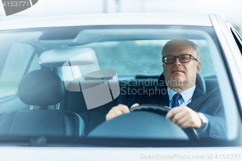 Image of happy senior businessman driving car