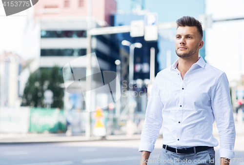 Image of young man walking along city street