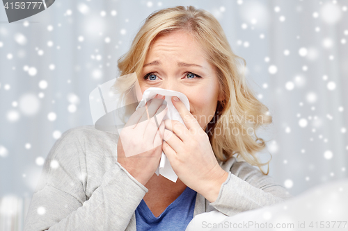 Image of ill woman blowing nose to paper napkin