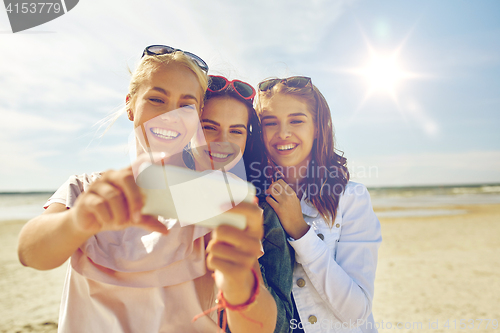 Image of group of smiling women taking selfie on beach