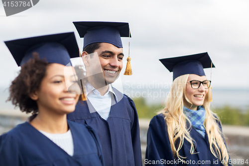 Image of happy students or bachelors in mortar boards