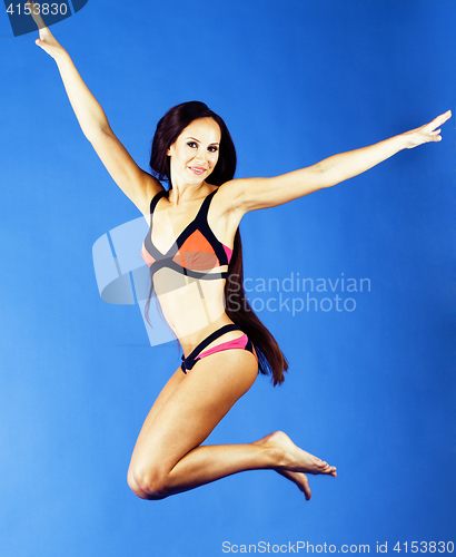 Image of young pretty smiling happy slim jumping girl in bikini on blue background, lifestyle people on vacation concept close up
