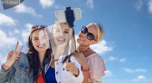 Image of group of smiling women taking selfie over blue sky