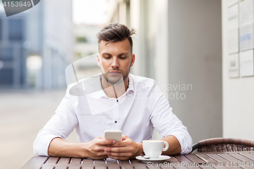 Image of man with smartphone and coffee at city cafe