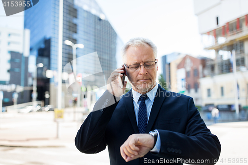 Image of senior businessman calling on smartphone in city