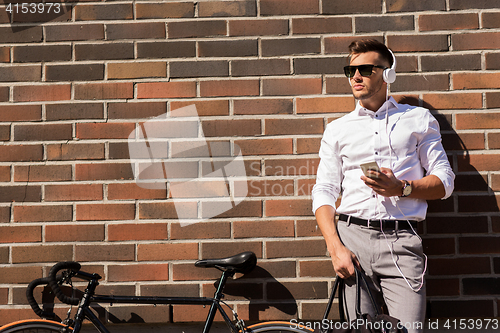 Image of man with headphones, smartphone and bicycle