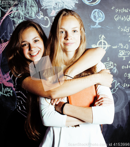 Image of back to school after summer vacations, two teen real girls in classroom with blackboard painted together