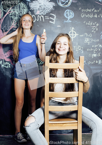 Image of back to school after summer vacations, two teen real girls in classroom with blackboard painted together