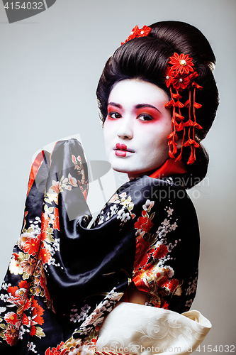 Image of young pretty geisha in black kimono among sakura, asian ethno