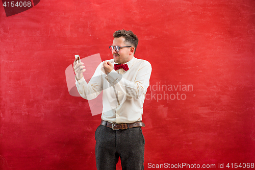 Image of Portrait of puzzled man talking by phone a red background