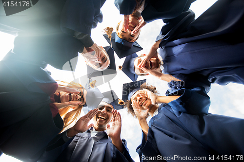 Image of happy students or bachelors in mortar boards