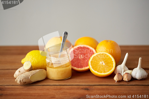 Image of honey, citrus fruits, ginger and garlic on wood