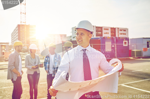 Image of architect with blueprint on construction site