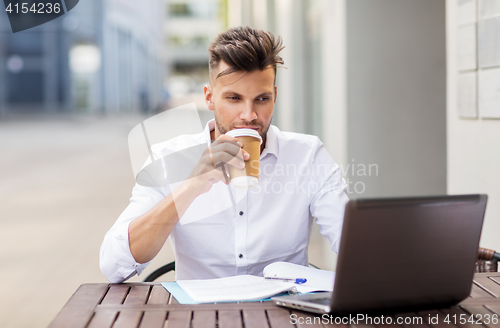 Image of man with laptop and coffee at city cafe