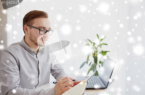 Image of creative man or businessman writing to notebook