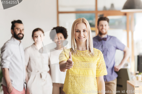 Image of woman showing thumbs up over creative office team