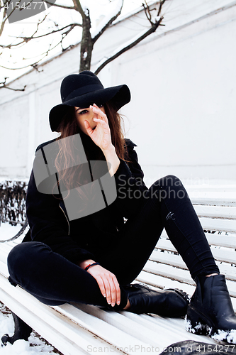 Image of young pretty modern hipster girl waiting on bench at winter snow park alone, lifestyle people concept