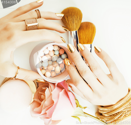 Image of woman hands with golden manicure and many rings holding brushes,