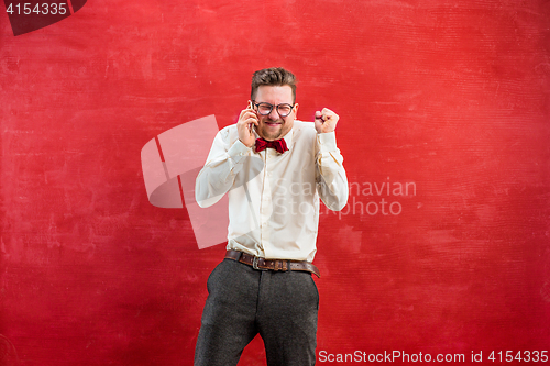 Image of Portrait of puzzled man talking by phone a red background