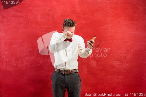 Image of Portrait of puzzled man talking by phone a red background