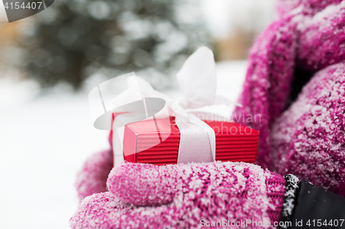 Image of close up of woman holding christmas gift outdoors