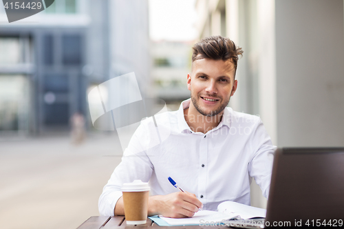 Image of man with laptop and coffee at city cafe