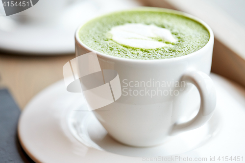 Image of white cup of matcha green tea latte on table