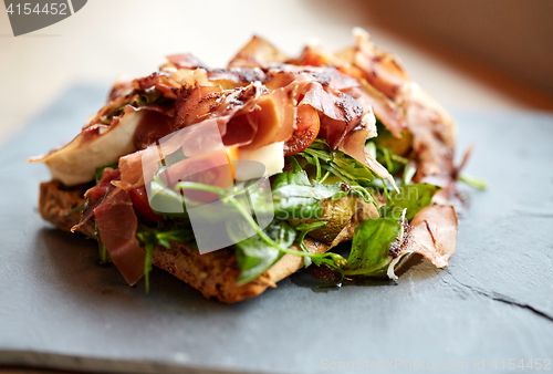 Image of prosciutto ham salad on stone plate at restaurant