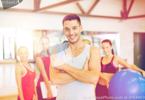 Image of smiling man standing in front of the group in gym