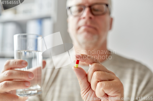 Image of close up of old man hands with pill and water