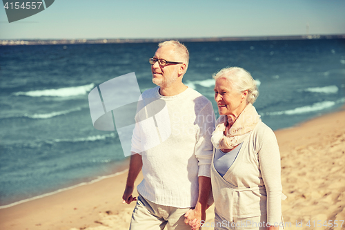 Image of happy senior couple walking along summer beach