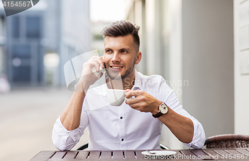 Image of man with coffee calling on smartphone at city cafe