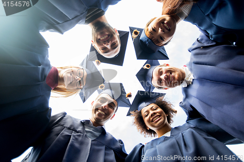 Image of happy students or bachelors in mortar boards