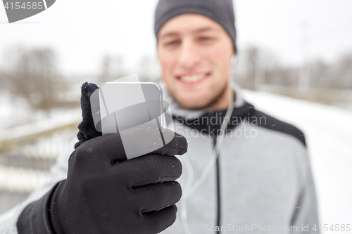 Image of happy man with earphones and smartphone in winter