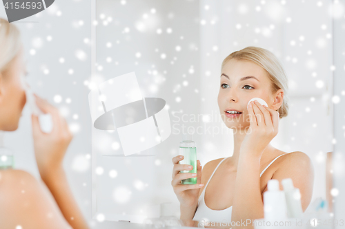 Image of young woman with lotion washing face at bathroom