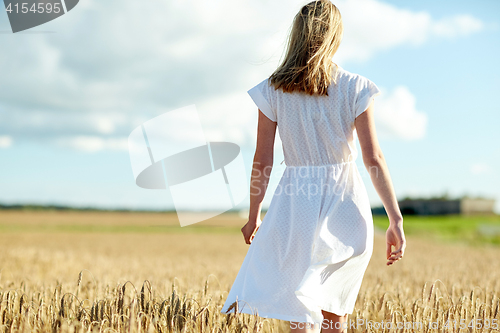Image of young woman in white dress walking along on field