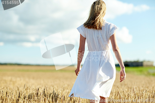 Image of young woman in white dress walking along on field