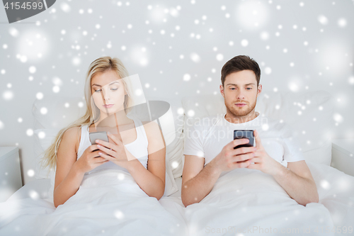 Image of couple with smartphones in bed