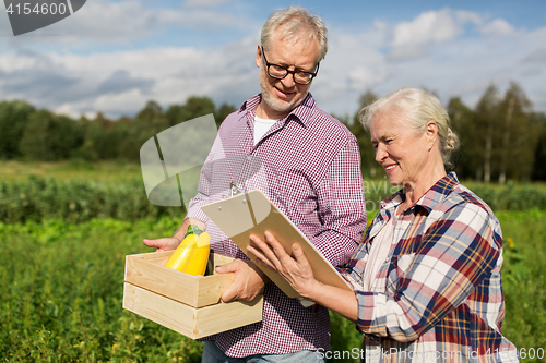 Image of senior couple with box of vegetables at farm