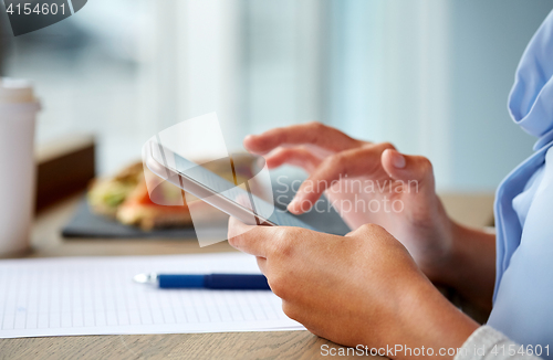 Image of woman with smartphone and food at cafe